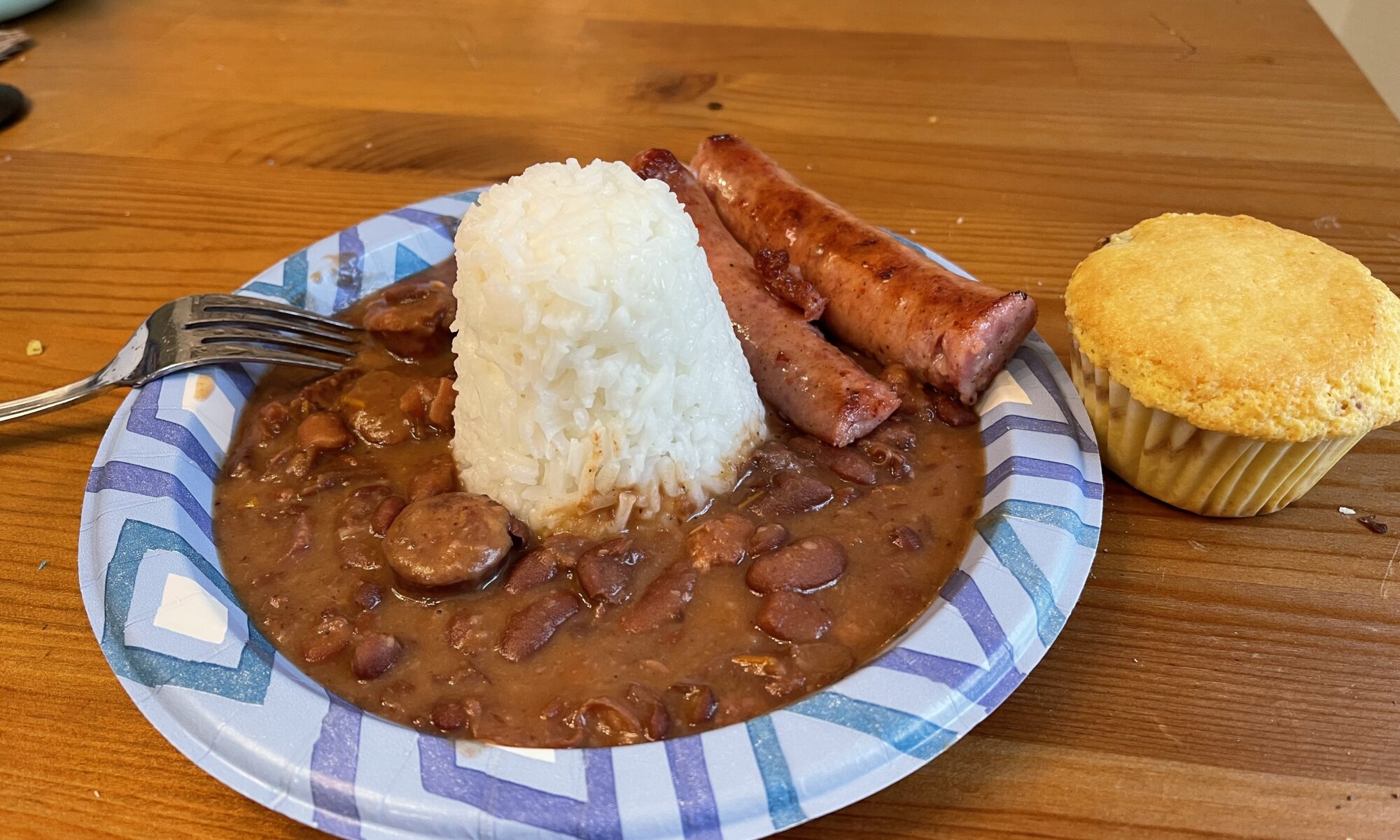 Red beans and rice, cornbread and smoked sausage on a paper plate