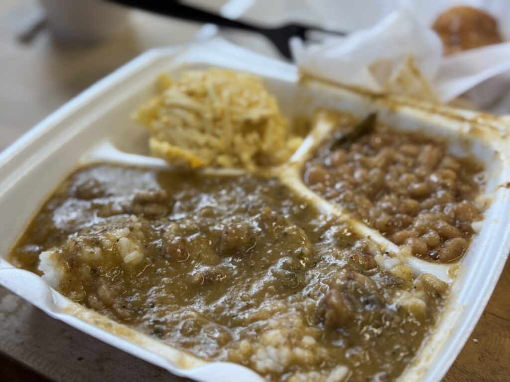 A styrofoam lunch plate of Spaghetti and Cheese, White beans and Rice with a main course of Crawfish Étouffée.